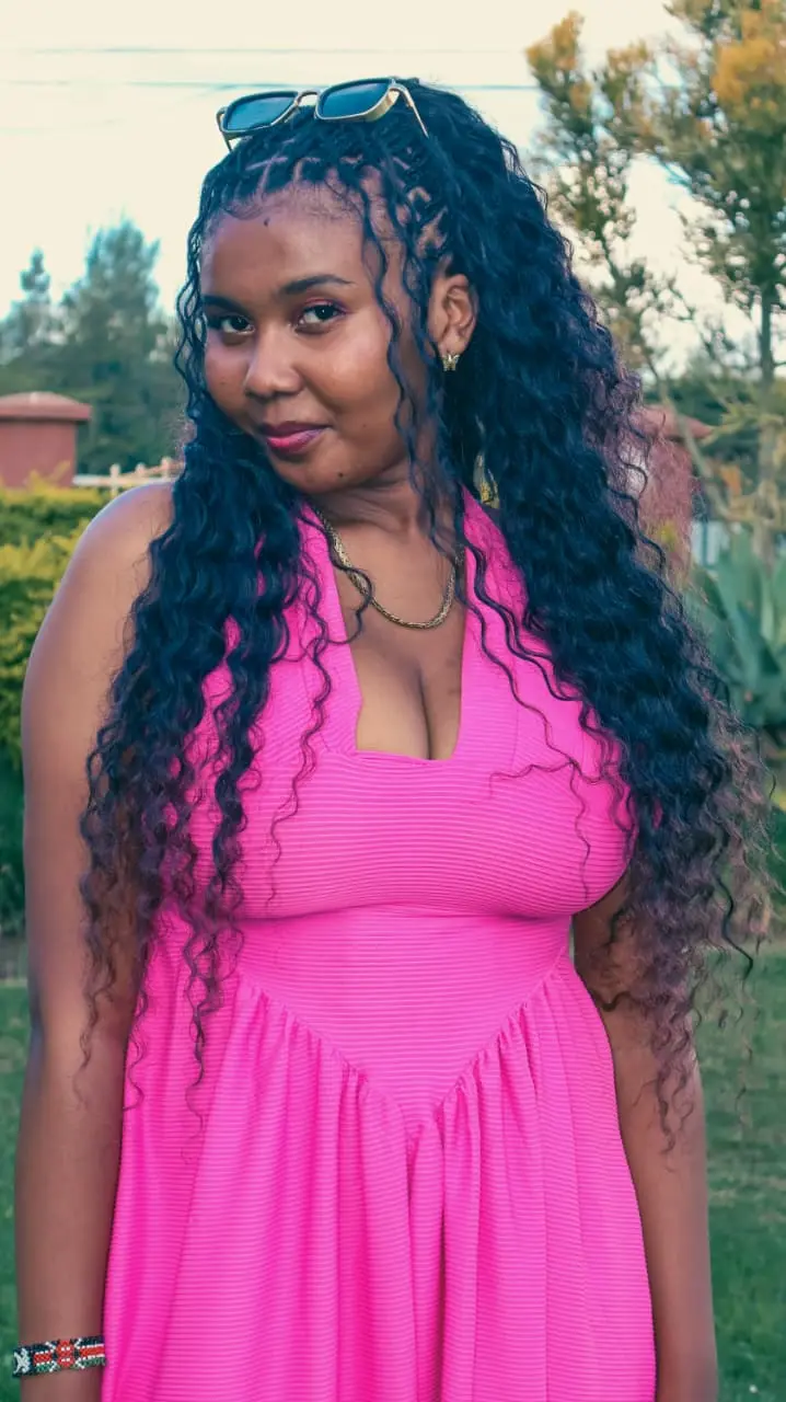 A woman in a pink halter dress with long curls, photographed in soft evening garden light